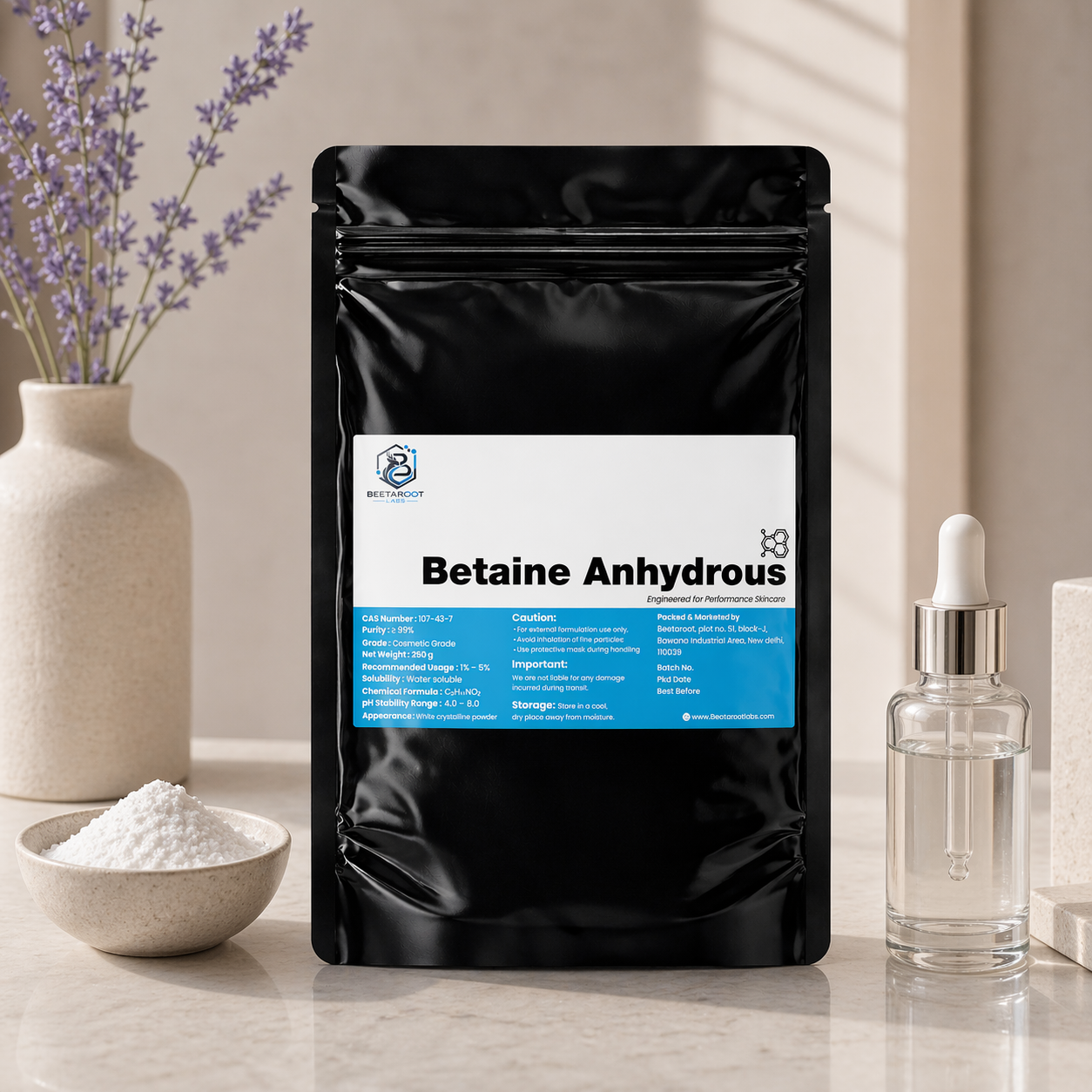 Black package of Betaine Anhydrous with a label, surrounded by a bowl of powder, a bottle, and lavender flowers.